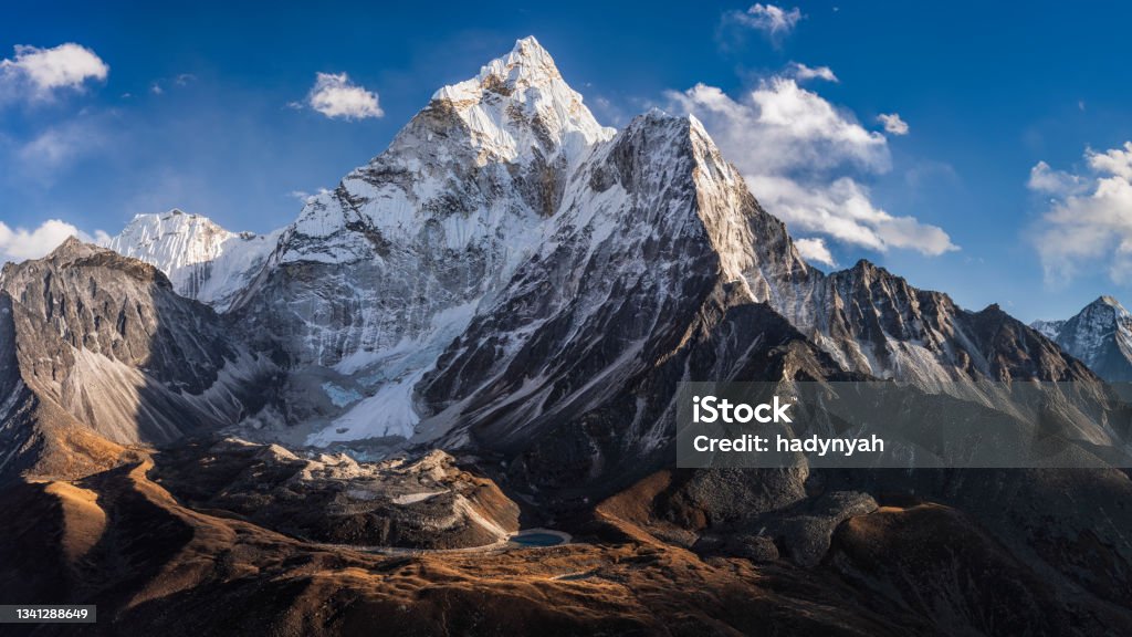 75MPix Panorama of beautiful Mount Ama Dablam in  Himalayas, Nepal 75MPix XXXXL size panorama of Mount Ama Dablam - probably the most beautiful peak in Himalayas. 
 This panoramic landscape is an very high resolution multi-frame composite and is suitable for large scale printing
Ama Dablam is a mountain in the Himalaya range of eastern Nepal. The main peak is 6,812  metres, the lower western peak is 5,563 metres. Ama Dablam means  'Mother's neclace'; the long ridges on each side like the arms of a mother (ama) protecting  her child, and the hanging glacier thought of as the dablam, the traditional double-pendant  containing pictures of the gods, worn by Sherpa women. For several days, Ama Dablam dominates  the eastern sky for anyone trekking to Mount Everest basecamp Mountain Stock Photo