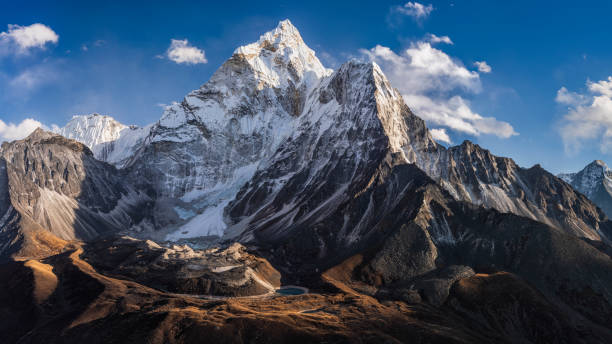 75MPix Panorama of beautiful Mount Ama Dablam in  Himalayas, Nepal 75MPix XXXXL size panorama of Mount Ama Dablam - probably the most beautiful peak in Himalayas. 
 This panoramic landscape is an very high resolution multi-frame composite and is suitable for large scale printing
Ama Dablam is a mountain in the Himalaya range of eastern Nepal. The main peak is 6,812  metres, the lower western peak is 5,563 metres. Ama Dablam means  'Mother's neclace'; the long ridges on each side like the arms of a mother (ama) protecting  her child, and the hanging glacier thought of as the dablam, the traditional double-pendant  containing pictures of the gods, worn by Sherpa women. For several days, Ama Dablam dominates  the eastern sky for anyone trekking to Mount Everest basecamp mountain range photos stock pictures, royalty-free photos & images
