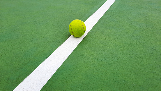 Close-up of tennis ball in green tennis field.