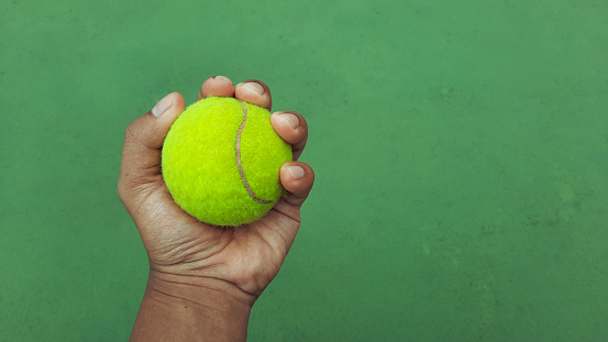 Man hand holding a tennis ball on court