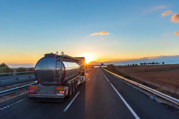 Photo of Food tanker truck driving on the highway with the dawn sun facing forward.