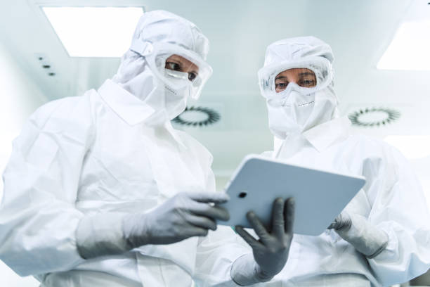 two female researchers in protective suits - protective suit fotos imagens e fotografias de stock