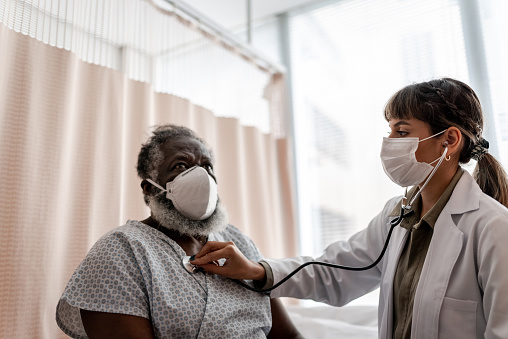 Doctor examining patient on medical appointment - wearing protective face mask