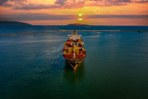 istock Loaded cargo container ship leaving port at sunset, 1341295279