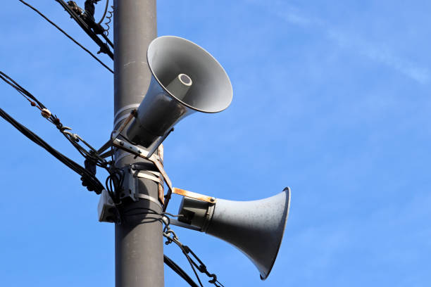 istock Loudspeakers on pole on blue sky background 1341295390