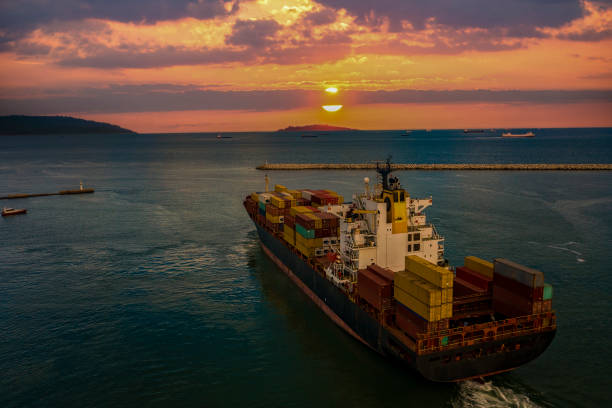 istock Loaded cargo container ship leaving port at sunset, 1341295636