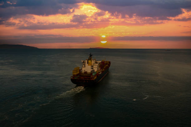 istock Loaded cargo container ship leaving port at sunset, 1341295753