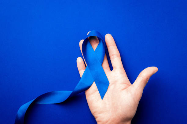 fita azul. conscientização do câncer de próstata da saúde dos homens em novembro. fita azul em mãos isoladas em fundo azul profundo. símbolo de oncologia afetada homem. copiar espaço. - cancro da próstata - fotografias e filmes do acervo