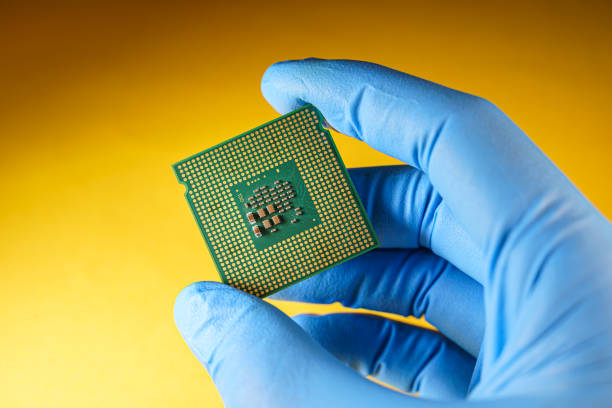 produzione di unità di elaborazione centrali, mano guantata tiene una cpu - scarcity foto e immagini stock