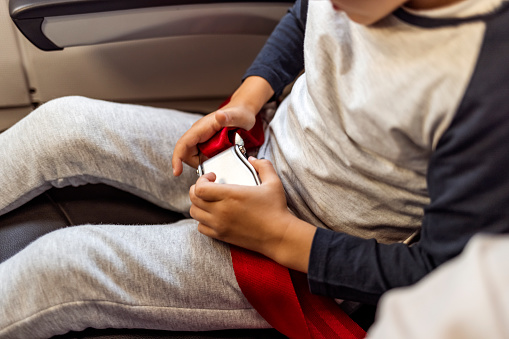 Unrecognizable child is fastening or unfasten her seat belt