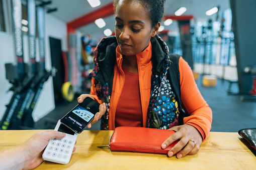 Mixed race woman in the gym paying with credit card