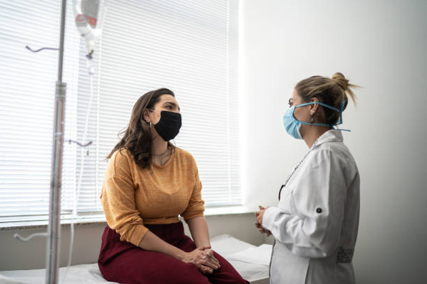 patient im gespräch mit arzt bei arzttermin - tragen einer schutzmaske - pollution mask stock-fotos und bilder