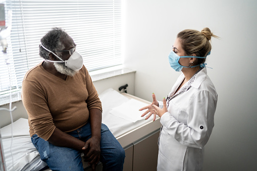 Patient talking to doctor on medical appointment - wearing protective face mask