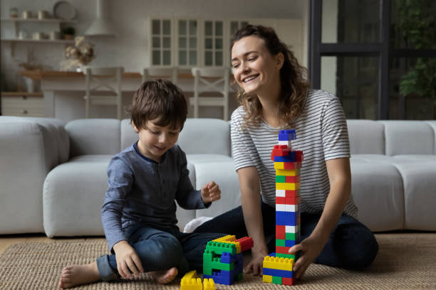 istock Happy mom helping son to build toy tower from blocks, 1341308138