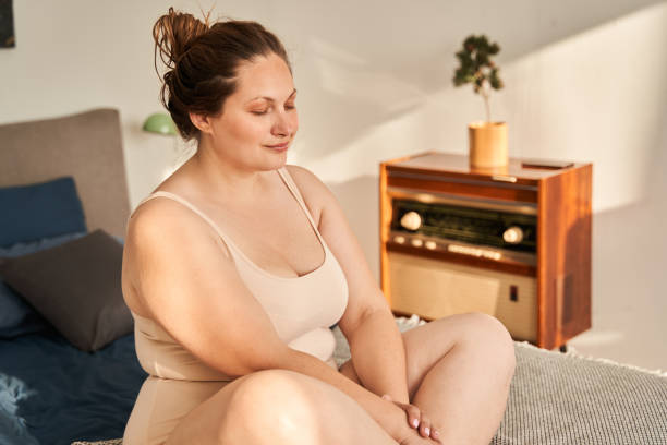 istock Oversize woman sit on bed and enjoy sunlight 1341308303