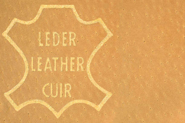 Genuine all natural beige tan leather swatch badge label tag horizontal background, multilingual English, French (FR cuir), German (DE Leder) golden printed text icon macro closeup, blank empty copy space, grained texture, large detailed textured pattern genuine all natural beige tan leather swatch badge label tag fondo horizontal, multilingüe inglés, francés (fr cuir), alemán (de leder) icono de texto impreso dorado macro closeup, espacio de copia vacío en blanco, textura granulada, patrón texturiza