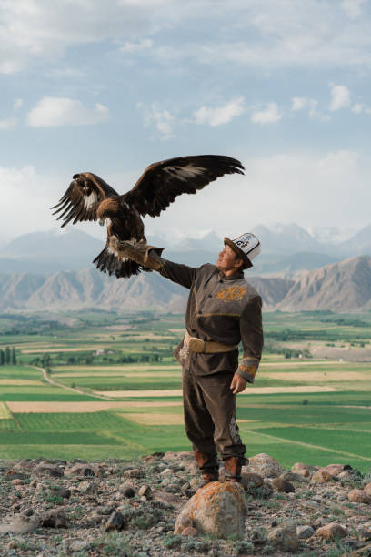 Eagle hunter standing on the background of mountains  in Kyrgyzstan Eagle hunter standing on the background of mountains  in Kyrgyzstan kyrgyzstan photos stock pictures, royalty-free photos & images