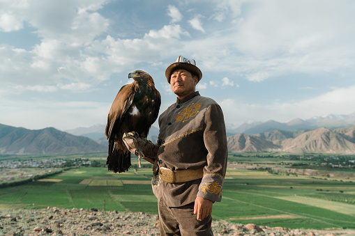 Eagle hunter standing on the background of mountains  in Kyrgyzstan