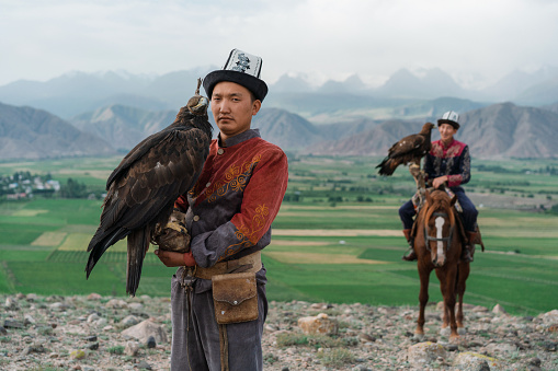 Two eagle hunters, one of them on horse, in steppe in Kyrgyzstan