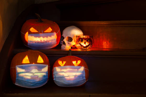 istock Lighted Halloween pumpkins Jack-o-Lantern with face masks for COVID 19 on steps 1341311467