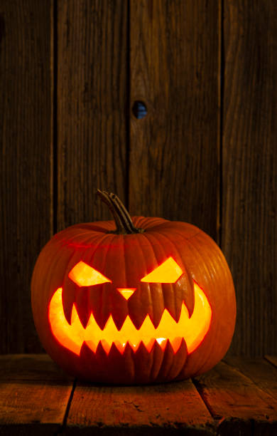 istock Scary face Halloween Jack O' lantern on rustic wooden dark background 1341311716