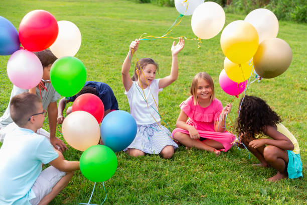 istock Barefoot kids playing with balloons on grass 1341312540