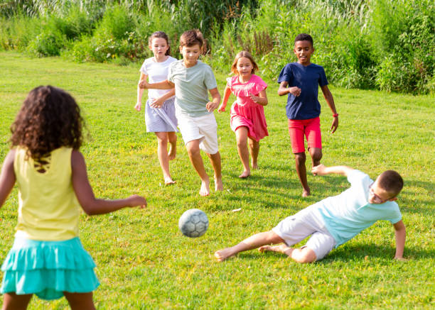 istock Kids running through grass and playing football 1341312542