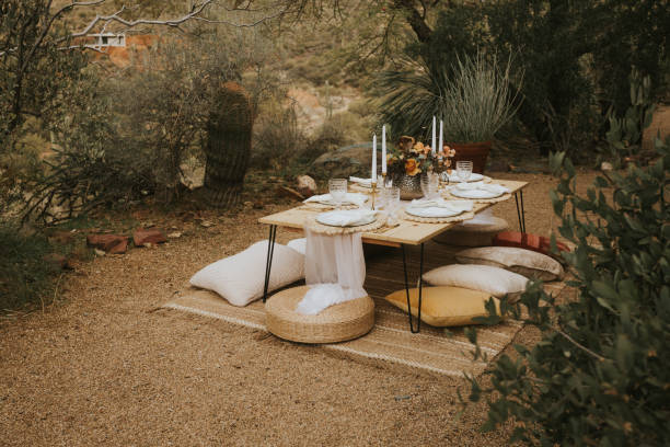 Modern bohemian style picnic A Moroccan style outdoor dining experience set up with floor table and floor cushions. Takes place in an outdoor patio in the desert. Styled with gold accents and pastel colors. This modern day picnic set up can be for engagement parties, wedding or elopement after parties, dinners with friends, wine tasting events and more. eloping stock pictures, royalty-free photos & images