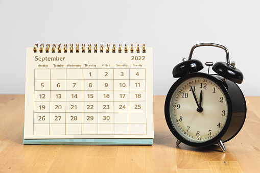 September 2022 calendar and vintage clock on a wooden table