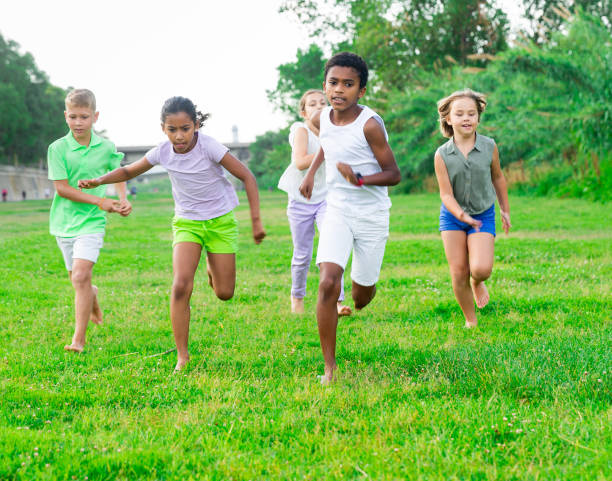 istock Five smiling kids running and laughing in park 1341314600