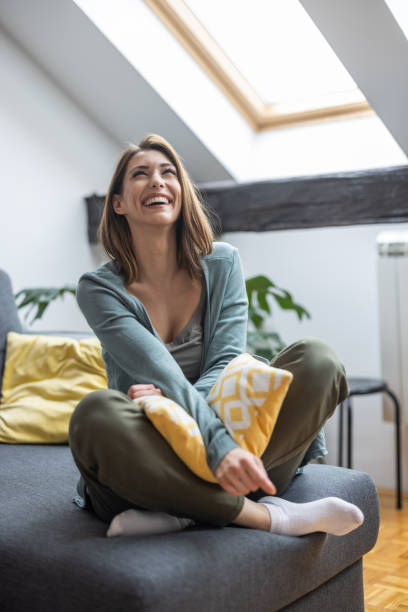 istock Happy cross legged woman sitting on sofa and laughing 1341317347