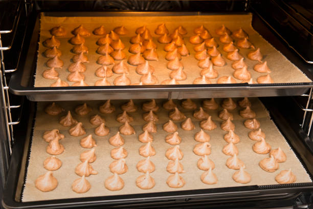 Oven with two baking sheets full with freshly baked mocha meringue.
