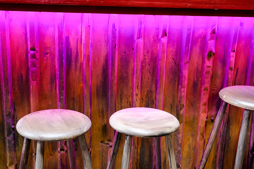 Lonely bar chairs in violett light with no people