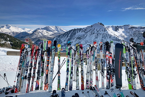 Montgenèvre, France - January 1, 2019:  A line of skis and snowboards stored on racks outside a cafe. Ski Resort in the Hautes Alpes