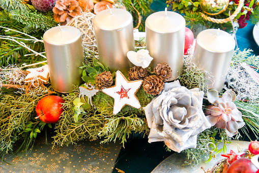 Christmas arrangement with four silver candles, roses, cookies, apples pine cones and fir branches