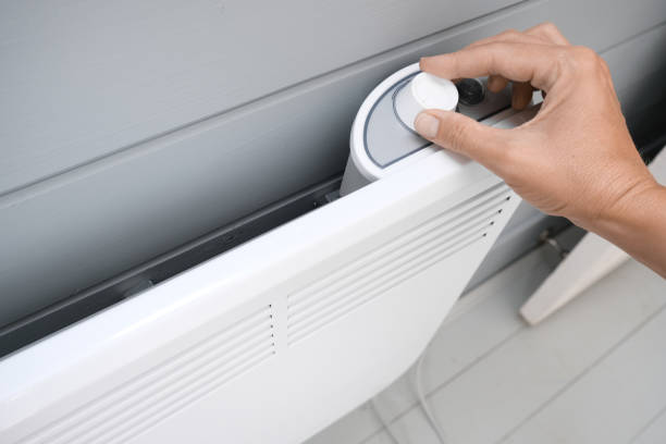 istock Hand regulating, setting temperature on electric convector, heater thermostate in the room in winter, climate control, home heating and energy saving concept 1341326583