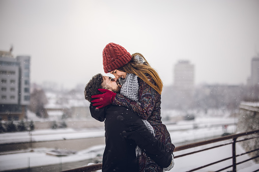 Young happy couple embracing each other on snowy day