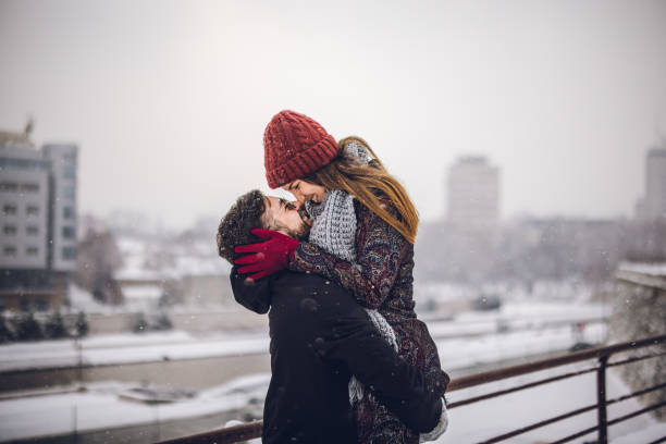 Happy couple embracing each other on snowy day stock photo