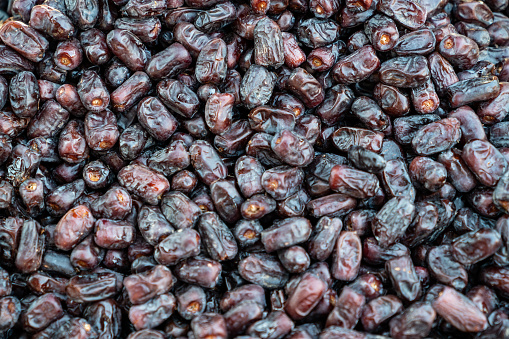 Full frame photo of black date palm fruit background. No people are seen in frame. Shot with a full frame mirrorless camera in outdoor.
