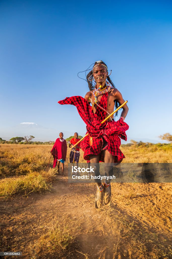Warrior from Maasai tribe performing traditional jumping dance, Kenya, Africa African warrior from Maasai tribe performing a traditional jumping dance, central Kenya, Africa - Mount Kilimanjaro on the background. Maasai tribe inhabiting southern Kenya and northern Tanzania, and they are related to the Samburu. Maasai People Stock Photo
