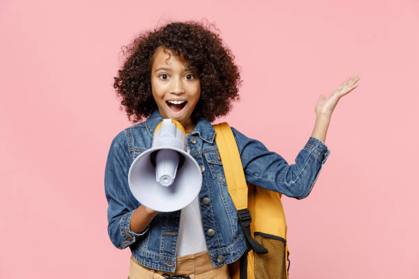 surprised leader little african american kid school girl 12-13 years old in casual clothes with backpack scream in megaphone spread hand isolated on pastel pink background childhood education concept. - 12 13 years fotos imagens e fotografias de stock