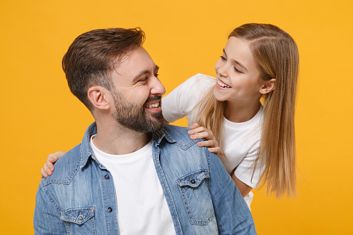 Funny bearded man in casual clothes have fun with cute child baby girl. Father little kid daughter isolated on yellow background. Love family day parenthood childhood concept. Looking at each other