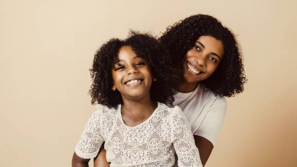 little girl and young black woman together looking at camera. mother and daughters hugging. - family child portrait little girls imagens e fotografias de stock