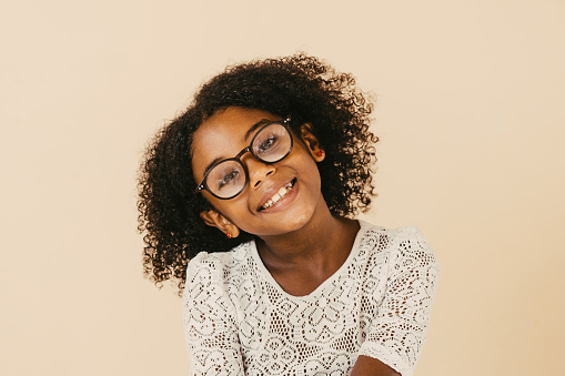 Headshot of preteen curly girl looking away against plain background