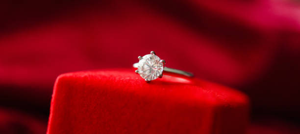 istock Diamond ring with jewelry gift box on red fabric background 1341347222