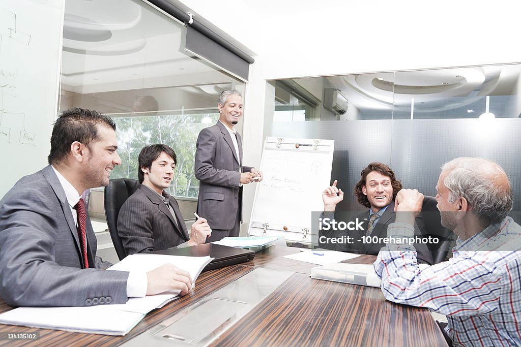 Giovane uomo d'affari dando presentazione ai suoi colleghi di felice - Foto stock royalty-free di Gruppo multietnico