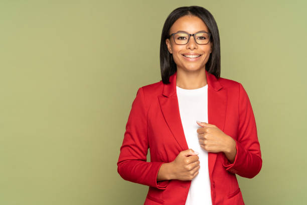 Positive confident african businesswoman, successful entrepreneur or business owner cheerful smiling Happy confident african american businesswoman, successful entrepreneur or small business owner female cheerful smiling and looking in camera. Black woman in eyeglasses and red jacket over studio wall blazer jacket stock pictures, royalty-free photos & images