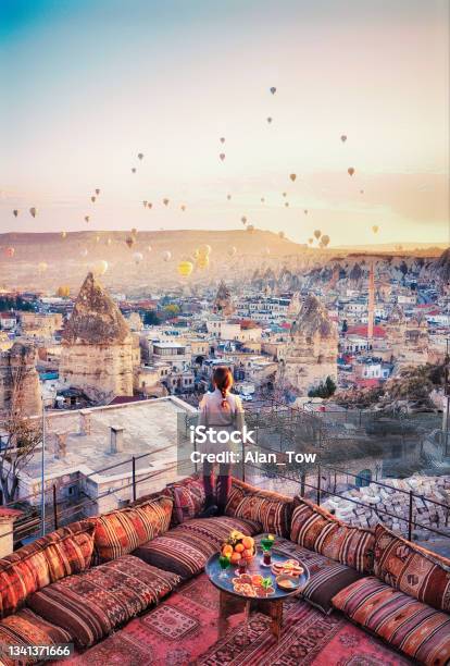 Beautiful Women Stand At Hotel Rooftop Watching Hot Air Balloons Flying Over City Ürgüp Cappadocia Turkey Stock Photo - Download Image Now