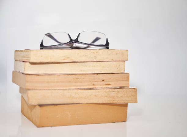 istock stack of book on white with reading glasses on top with copy space 1341372756
