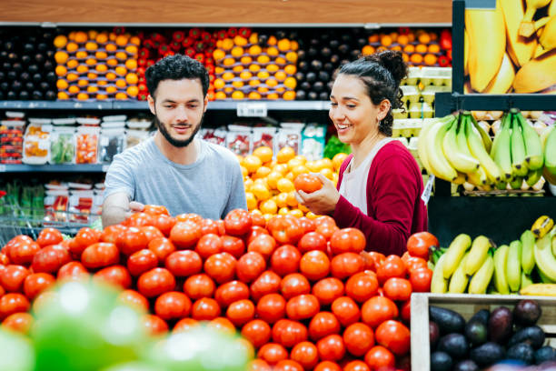 couple achetant des tomates au supermarché - supermarket discussion people talking photos et images de collection